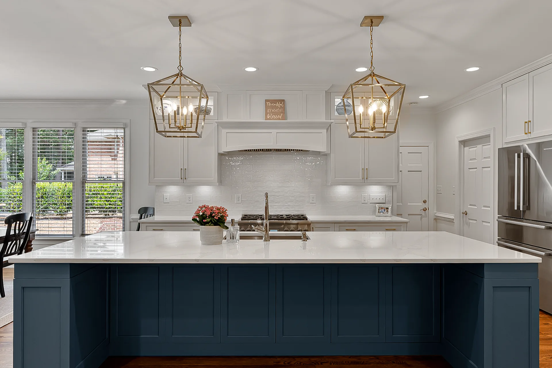 Kitchen remodel with navy blue island, brass lantern pendants, and white cabinets