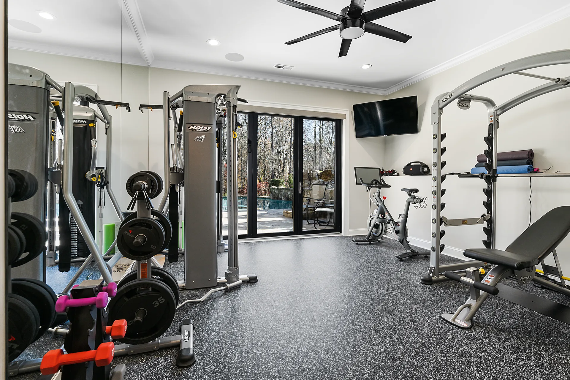 Finished basement home gym with rubber flooring, mirrored wall, and exercise equipment