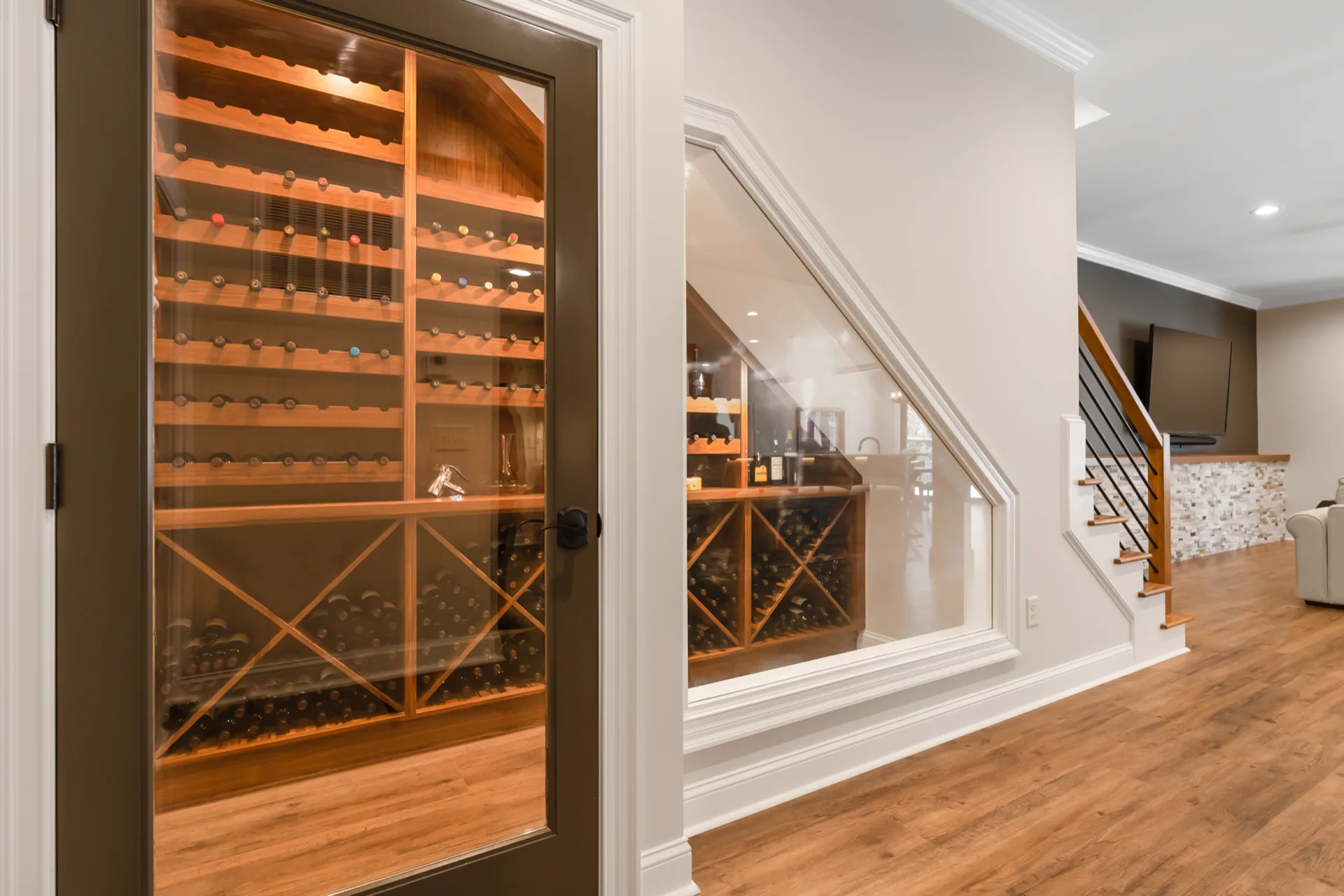 Basement wine cellar with glass door tucked under the staircase