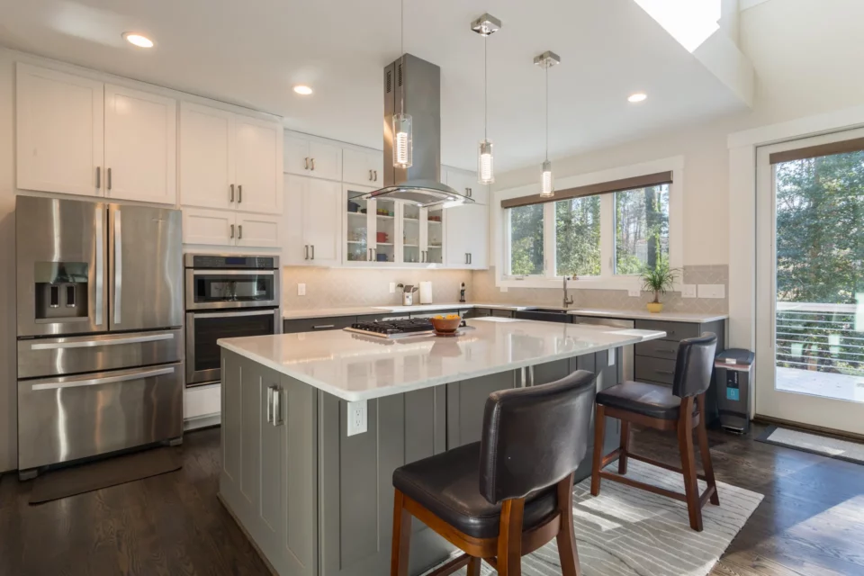 Kitchen detail showing white shaker cabinets, gray island with quartz top, gas cooktop with island hood, and glass-front uppers